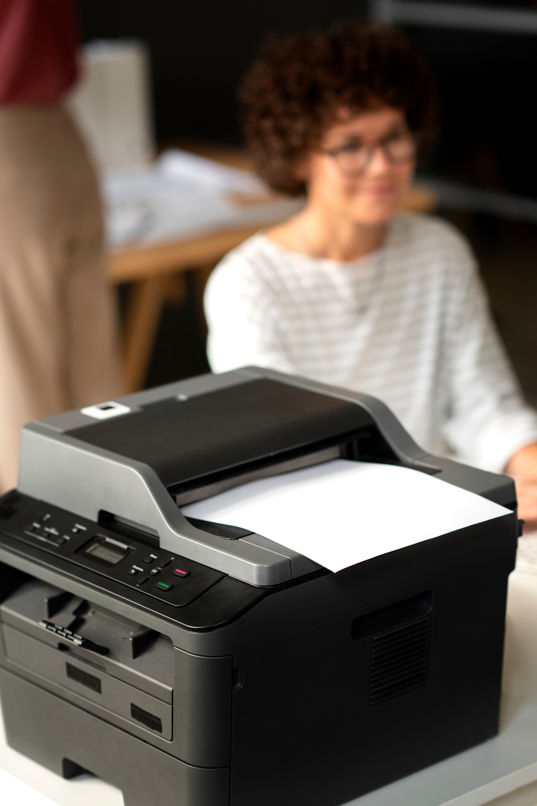 Mulher sorrindo ao lado de uma impressora